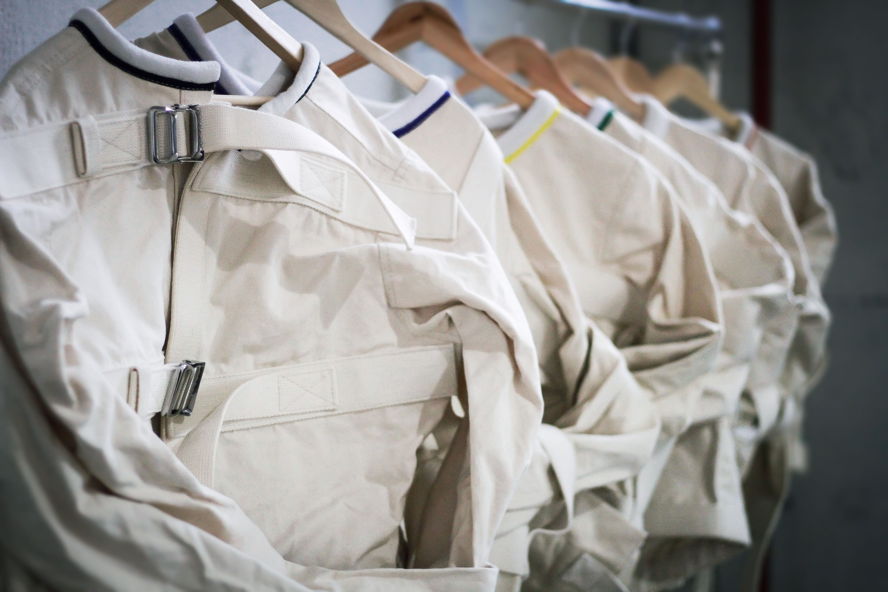 Row of canvas straitjackets hanging on wooden hangers