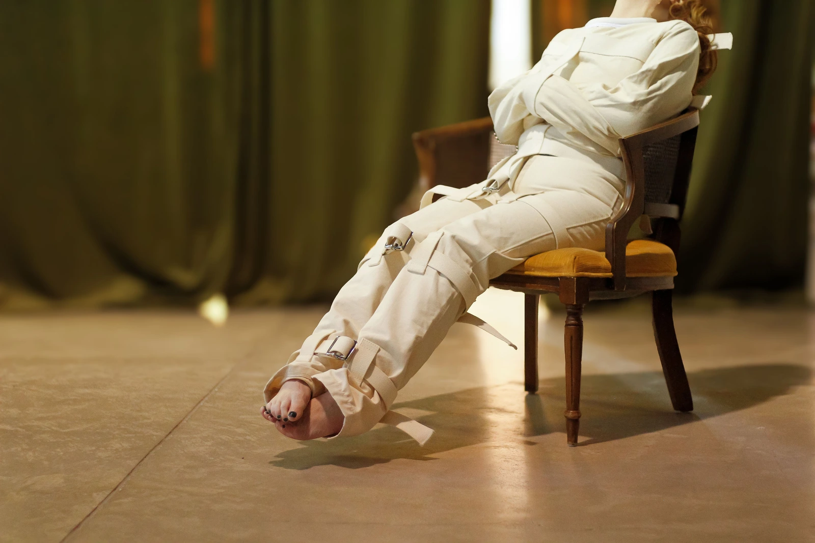 Seated wearer in a Canvas Posey Replica with the white canvas sleeves crossed in front.