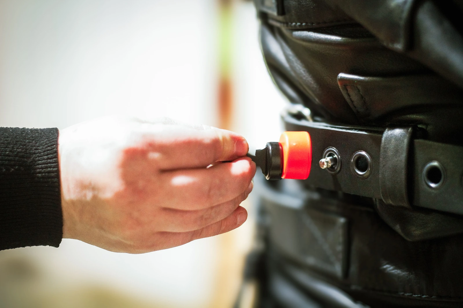 Close-up of a magnetic key releasing a lock on a Leather Posey Replica buckle.